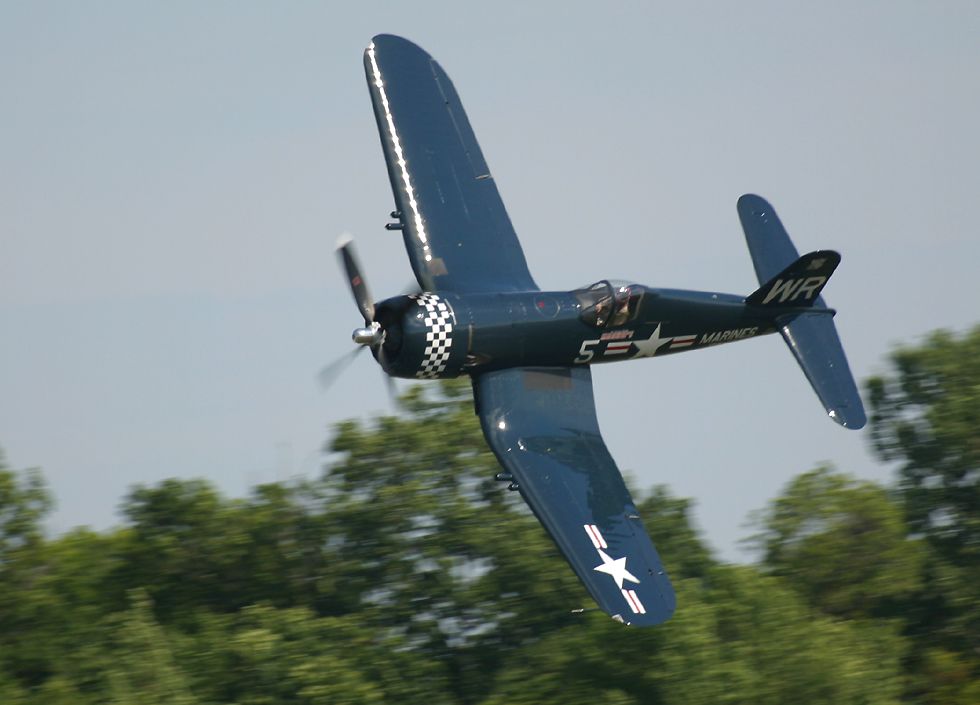 F4U Corsair banking steeply at treetop level