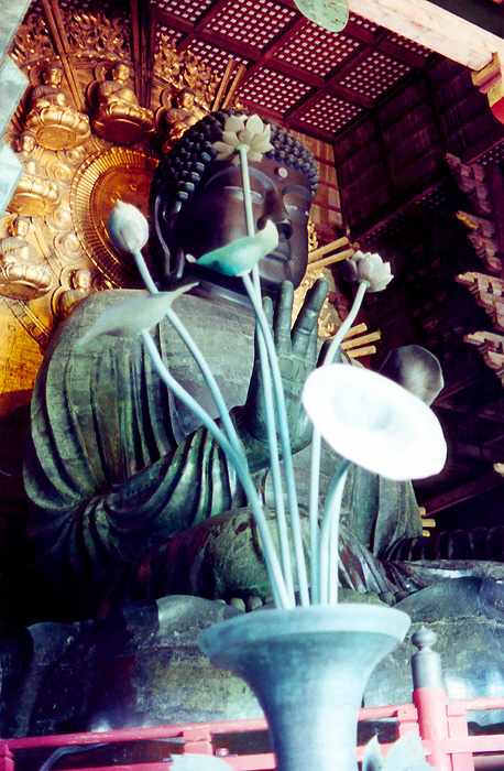 Buddha statue with large bronze lotus vase in foreground