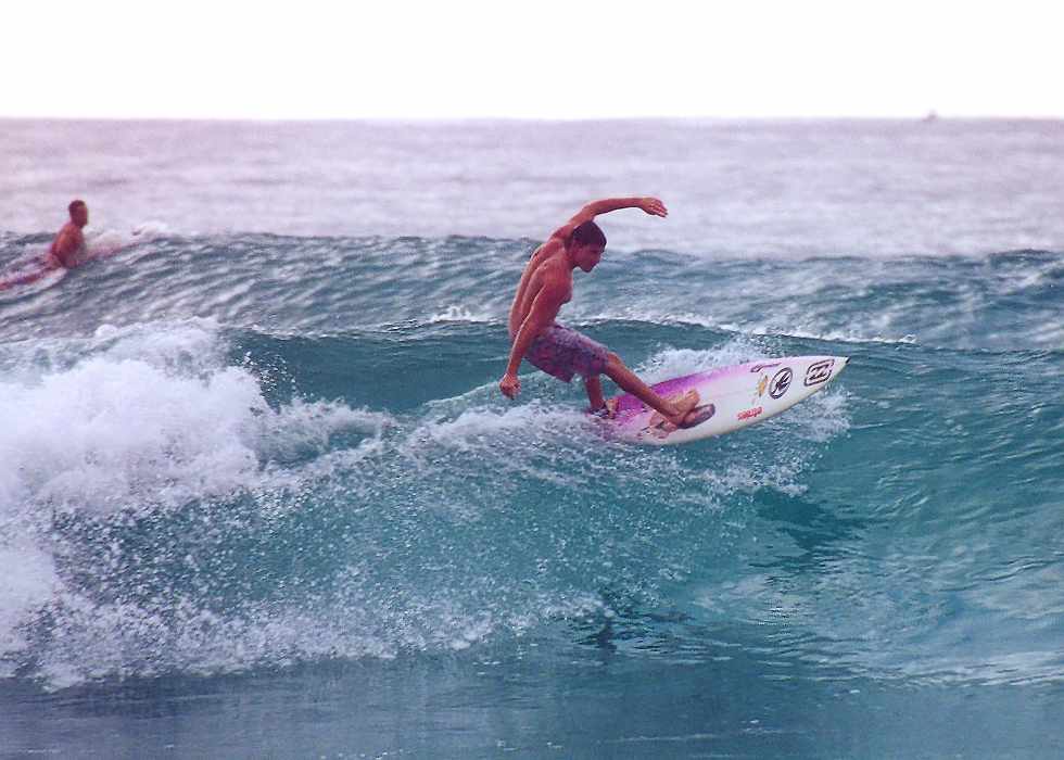 surfer rides one wave, while another surfer sits out the next